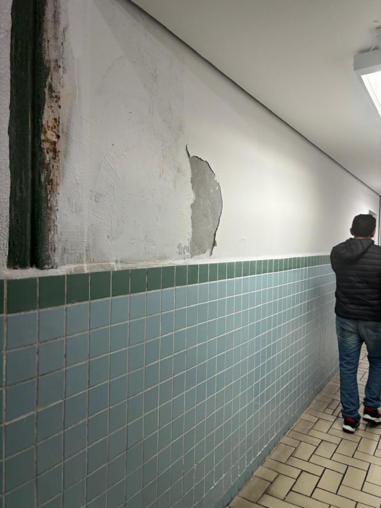 Corredor com parede danificada antes do reparo