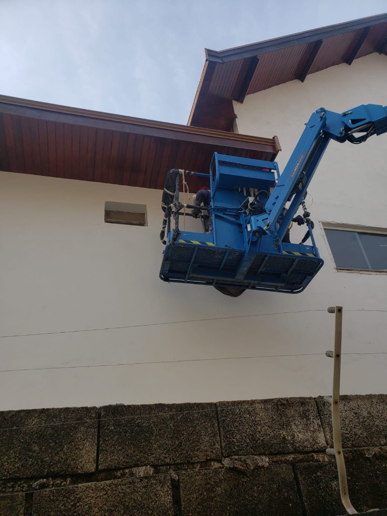 Plataforma elevatória posicionada em fachada para serviço de pintura